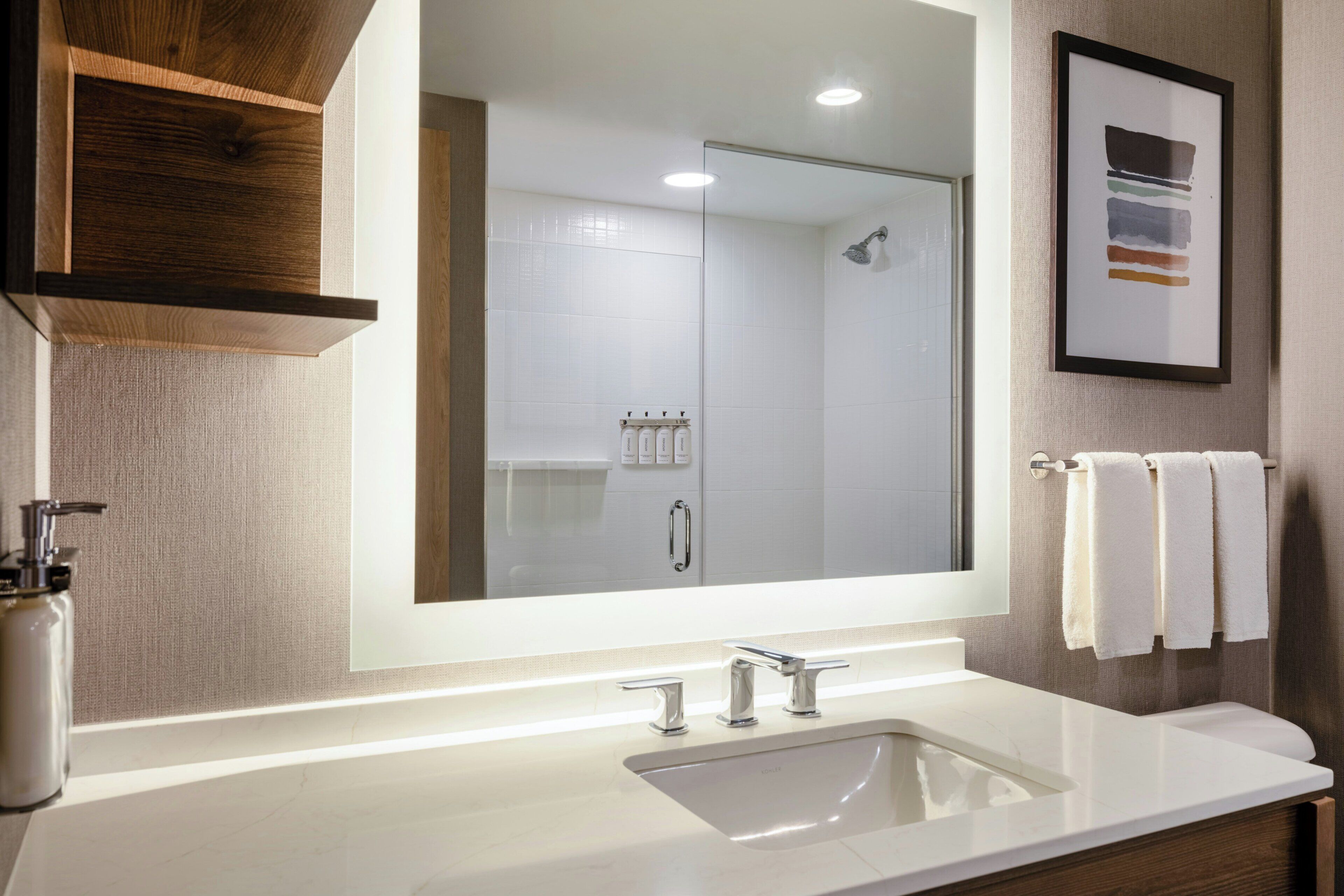 A bathroom with a large mirror, a sink, a shower, and a towel rack.
