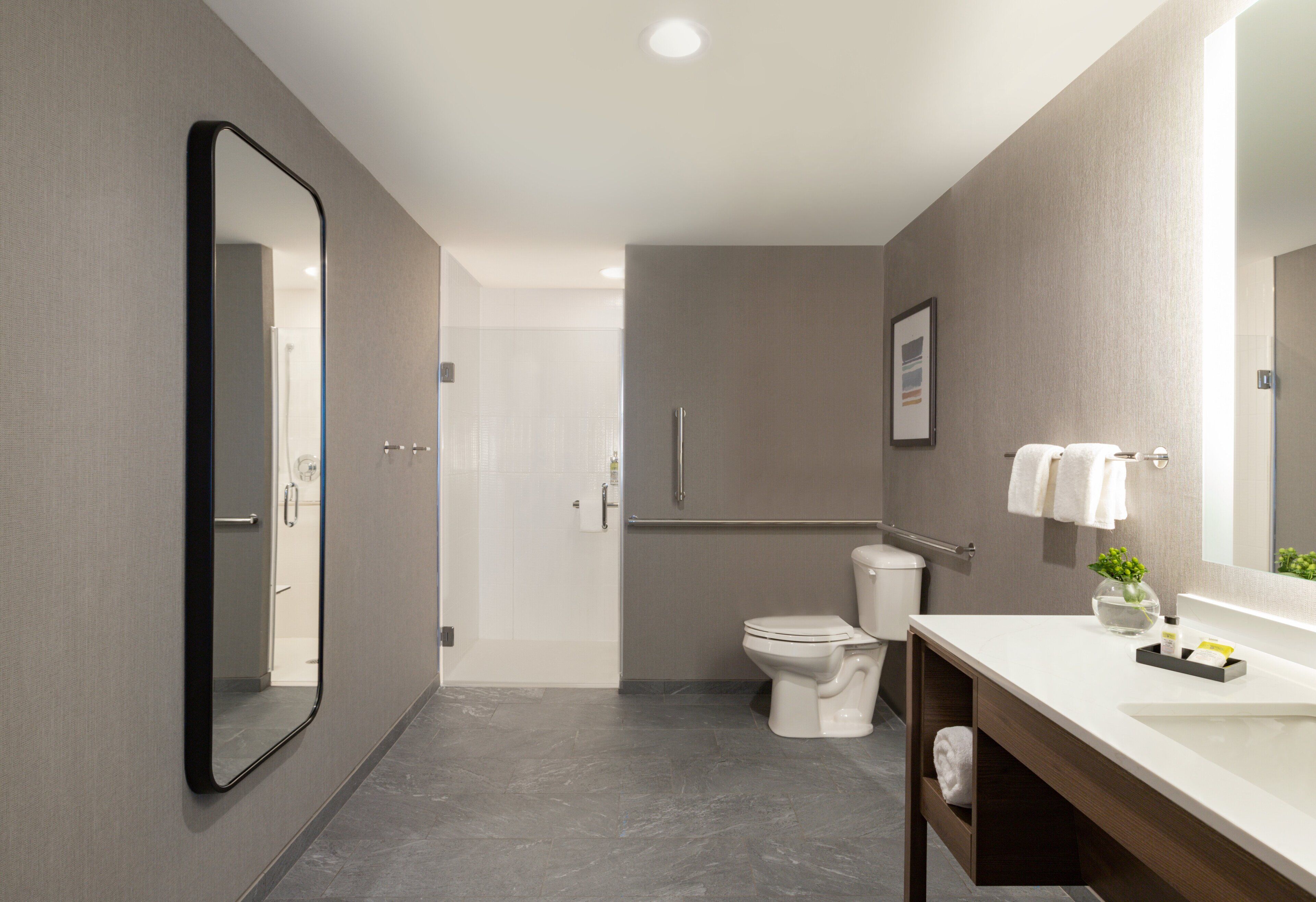 A modern bathroom with a toilet, bidet, and a large mirror.
