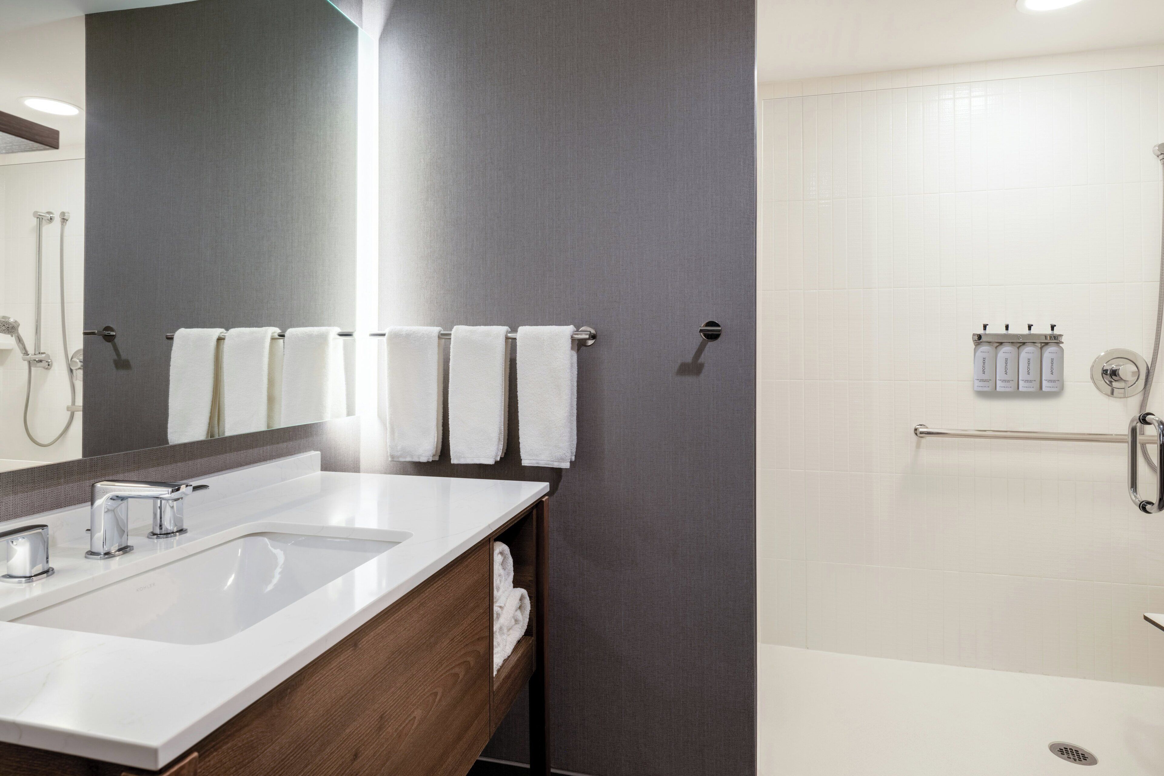 Un baño moderno con un tocador de doble lavamanos, un espejo grande y una zona de ducha con puerta de cristal.