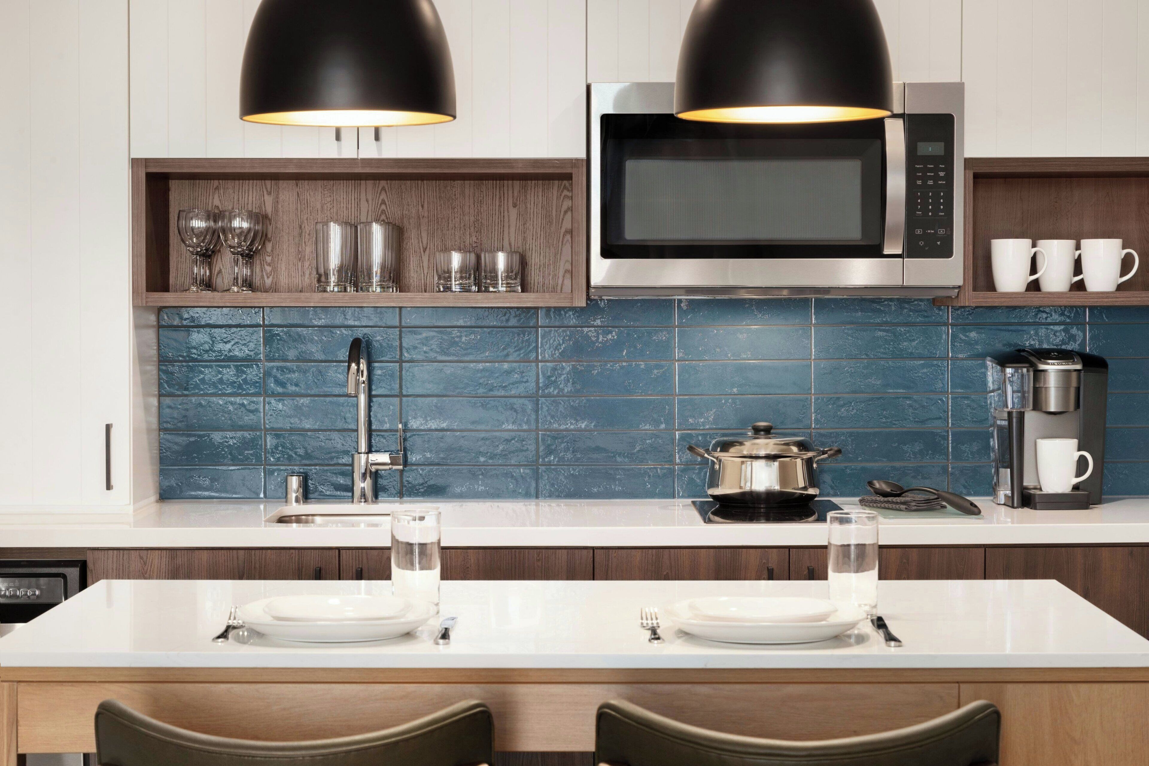 A modern kitchen with a microwave, coffee maker, and a dining area with a white table and chairs.