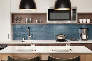 A modern kitchen with a microwave, coffee maker, and a dining area with a white table and chairs.