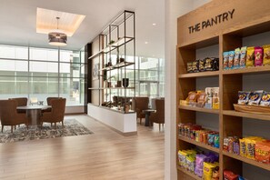 A modern interior with a dining area, a kitchen, and a pantry stocked with snacks.