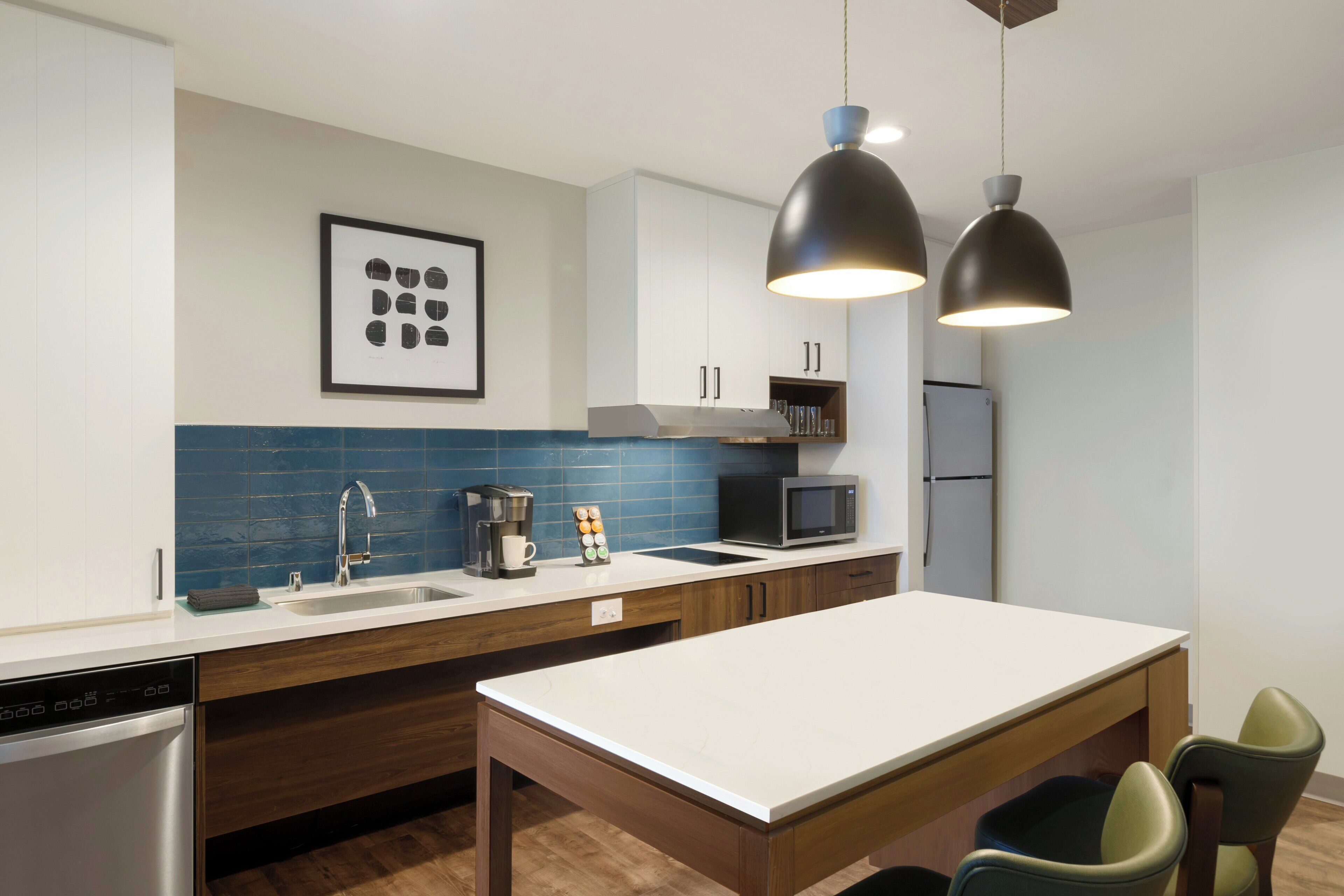 A modern kitchen with a white countertop, a coffee machine, a microwave, and a dishwasher.