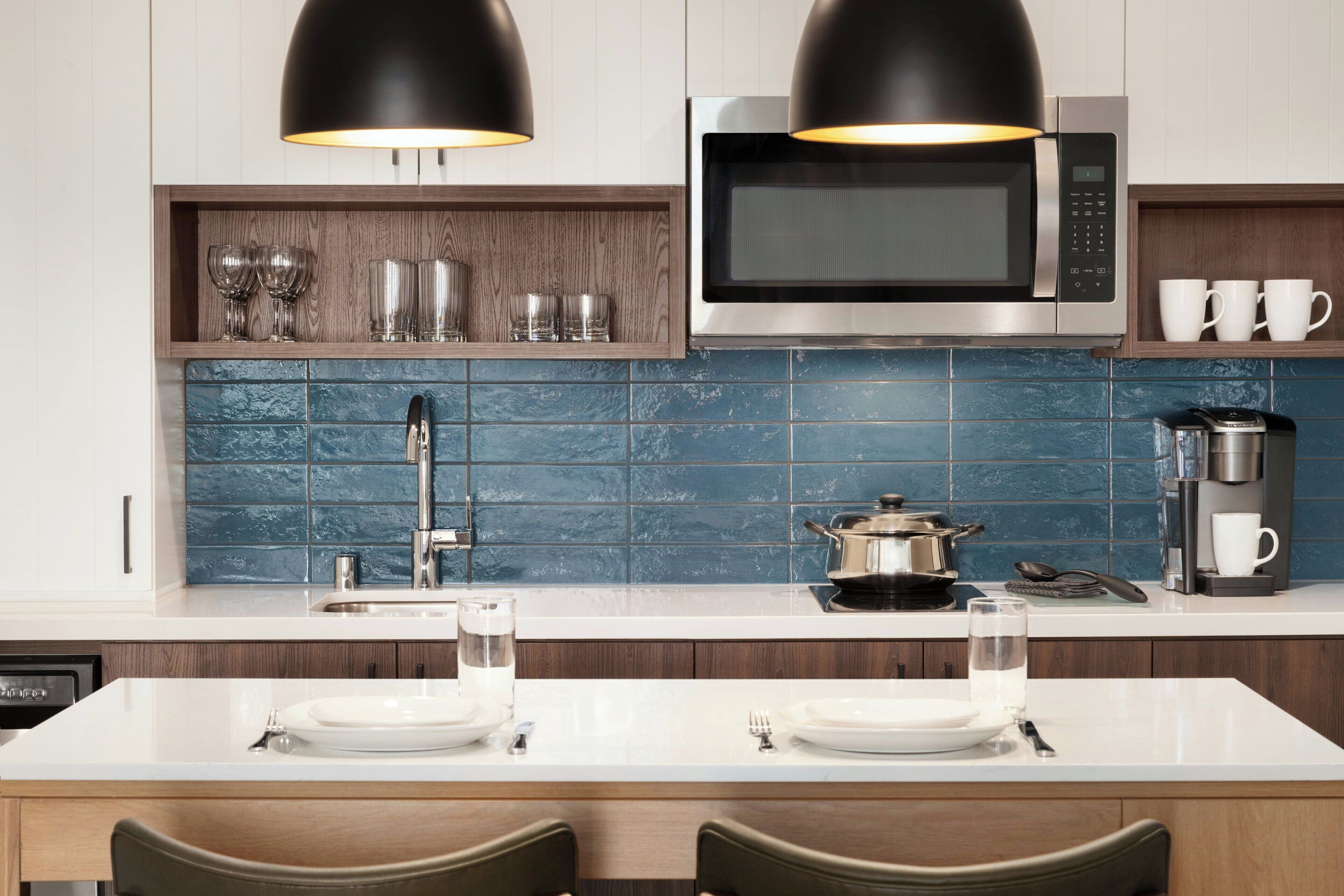 A modern kitchen with a microwave, coffee maker, and a dining area with a white table and chairs.