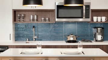 A modern kitchen with a microwave, coffee maker, and a dining area with a white table and chairs.