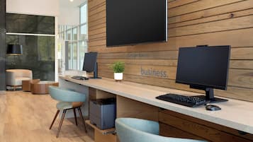 A modern office reception area with a long desk, two monitors, a keyboard, a mouse, and a potted plant.