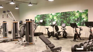 Ein Fitnessstudio mit verschiedenen Trainingsgeräten, darunter Laufbänder, Ergometer und Kraftgeräte.