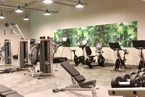Ein Fitnessstudio mit verschiedenen Trainingsgeräten, darunter Laufbänder, Ergometer und Kraftgeräte.