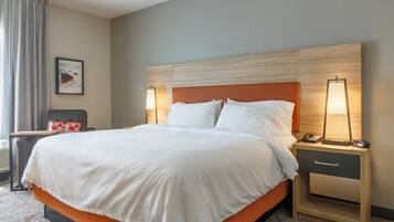 A hotel room with a large bed, two bedside tables, a chair, a lamp, and a painting on the wall.
