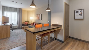 A modern hotel room with a kitchenette, a dining area, and a seating area with a sofa and chairs. - Candlewood Suites San Antonio Schertz by IHG (Schertz)