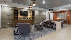 A modern living room with a wooden accent wall, a flat-screen TV, a dining area with a table and chairs, and pendant lighting. - Candlewood Suites San Antonio Schertz by IHG (Schertz)