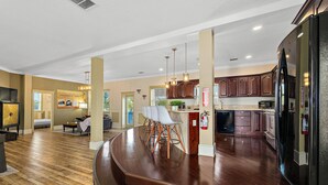 A spacious kitchen with wooden flooring, a curved bar area, and modern appliances. - The Ray - Penthouse Suite - Rooftop View (St. Augustine)