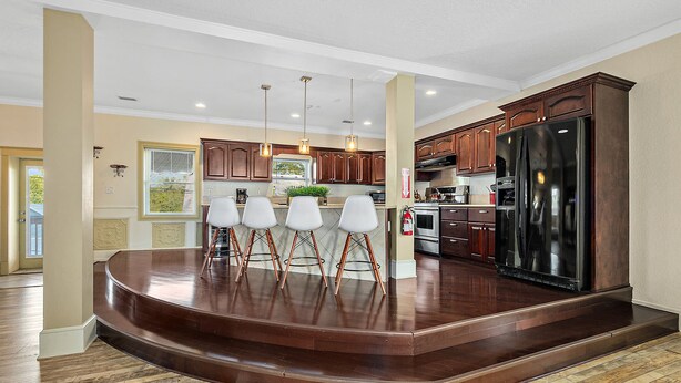 A kitchen with a central island, wooden cabinets, and pendant lighting. - The Ray - Penthouse Suite - Rooftop View (St. Augustine)