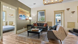 A living room with a sofa, coffee table, and a wall with a poster. - The Ray - Penthouse Suite - Rooftop View (St. Augustine)
