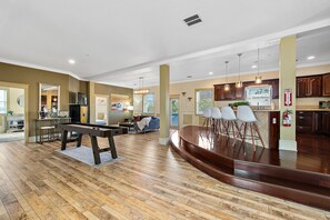 A spacious living area with a pool table, a bar area, and a kitchen in the background. - The Ray - Penthouse Suite - Rooftop View (St. Augustine)