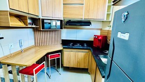 A compact kitchen with wooden cabinets, a black refrigerator, a microwave, and a gas stove.