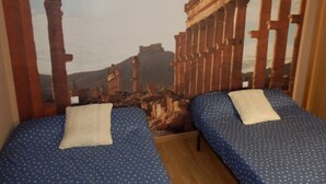 A room with two beds, each with a blue polka dot bedspread and white pillows.