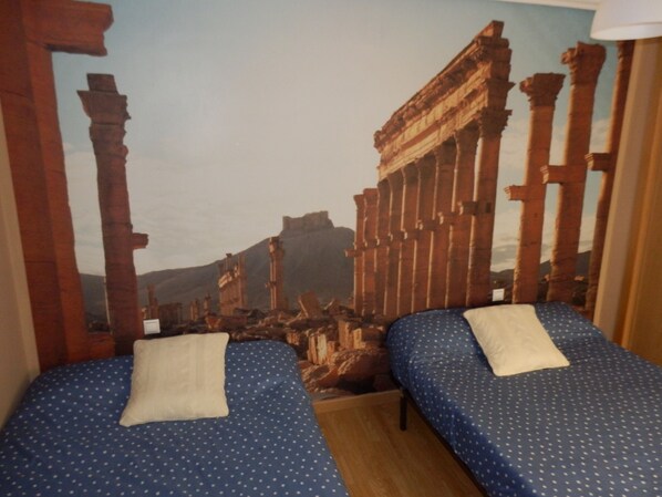 A room with two beds, each with a blue polka dot bedspread and white pillows.