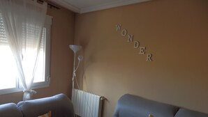A living room with two sofas, one with orange and white striped pillows, and a wall with the word "WONDER" spelled out in letters.