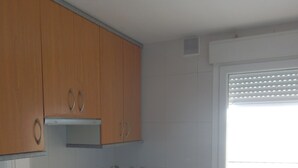 A kitchen with wooden cabinets, a black countertop, and a stainless steel stove.