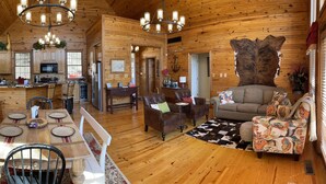 A spacious log cabin interior with a dining area, kitchen, and living room.