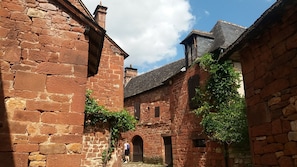 A narrow alleyway between stone buildings with arched doorways and a clear sky.