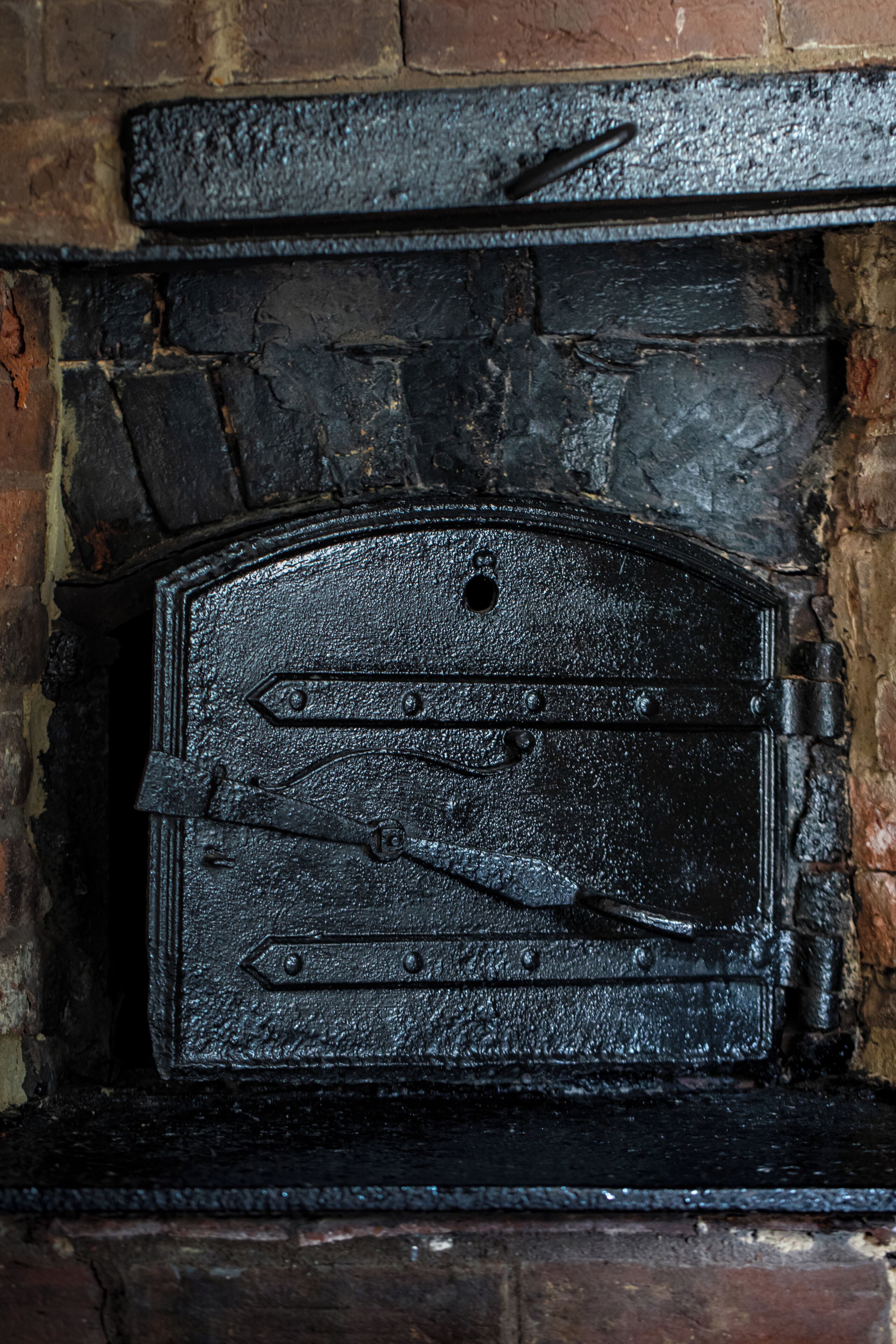 Una chimenea de metal negro con puerta abatible, instalada en una pared de ladrillo.