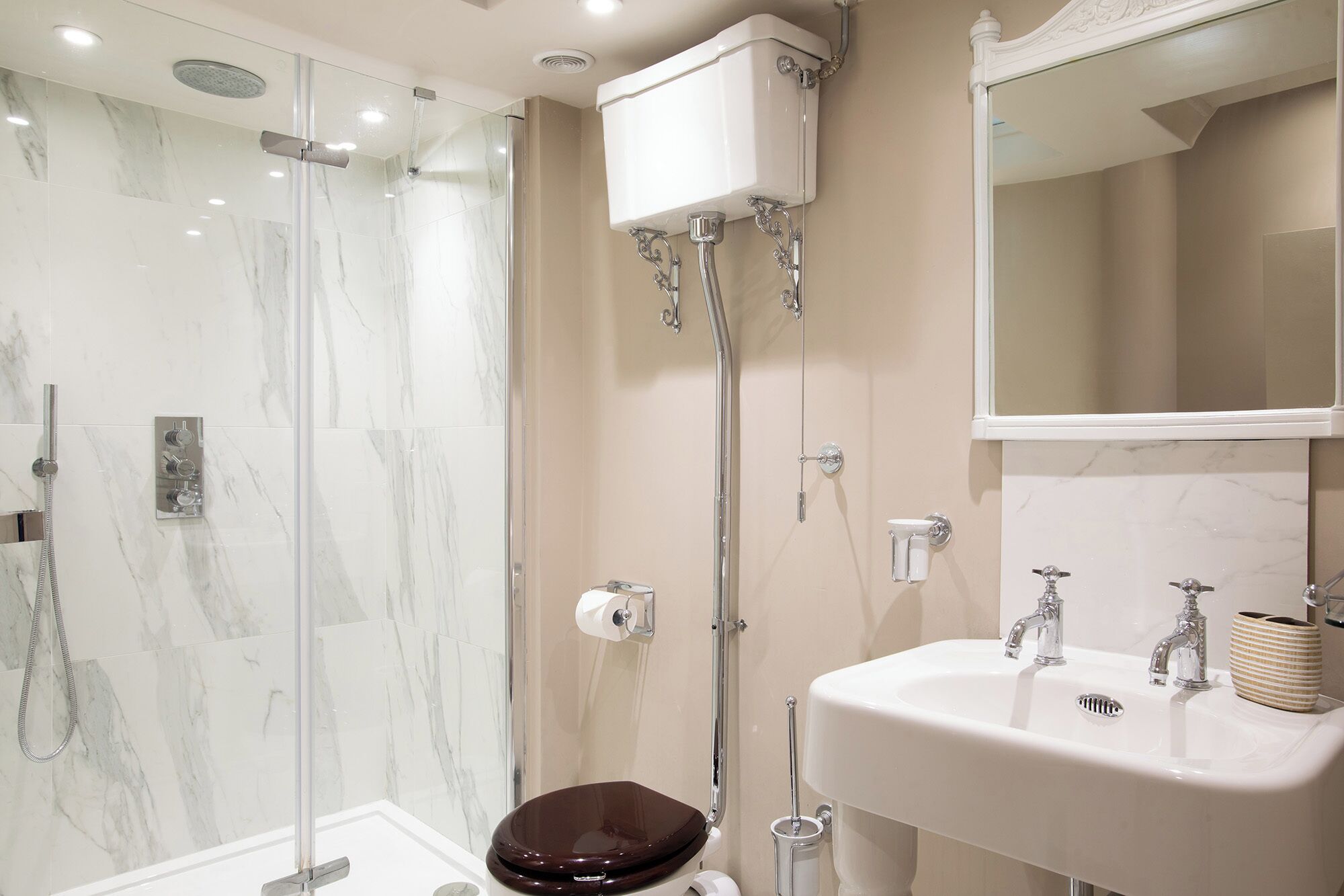 A modern bathroom with a glass-enclosed shower, a toilet, and a sink with a mirror above it.