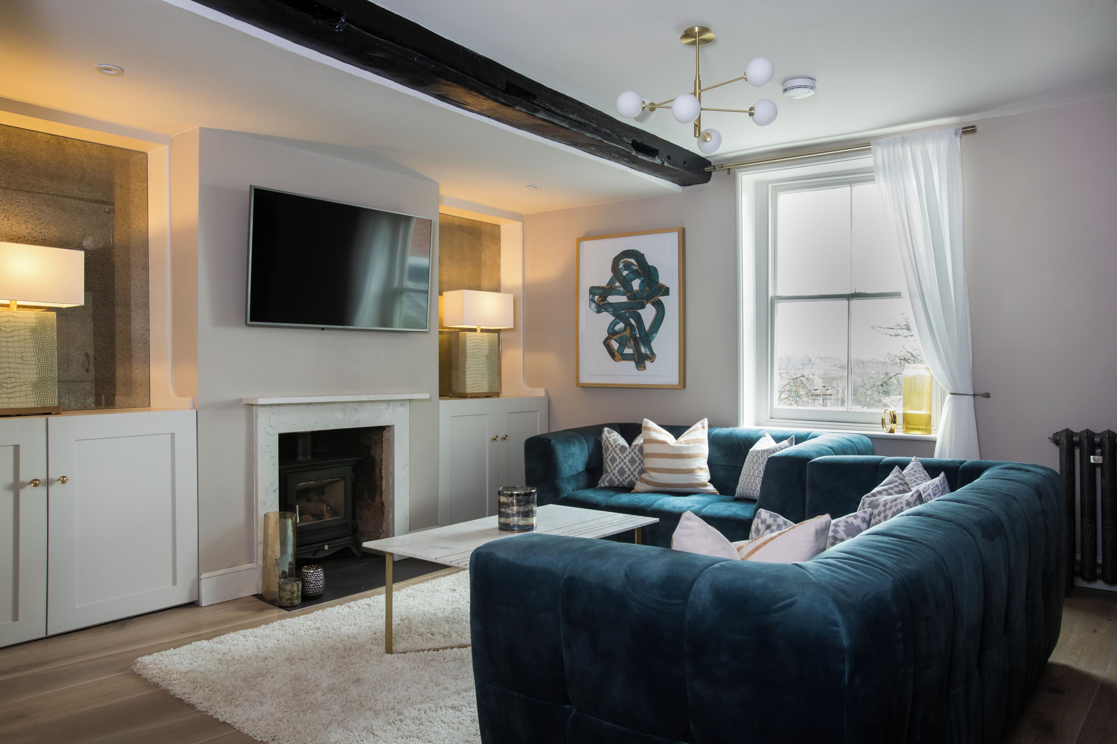A modern living room with a fireplace, a large TV, and a cozy sofa.