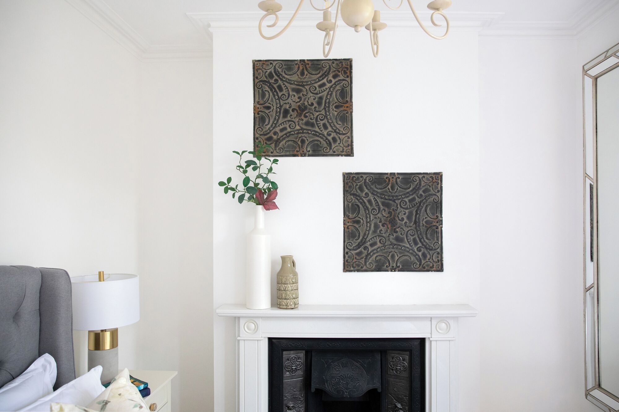 A room with a white fireplace, a grey armchair, and a white lamp.