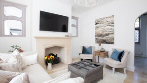A living room with a fireplace, a television, and a painting on the wall. - Beautiful Iconic Listed Building with Views Overlooking the Arundel Cathedral (Arundel)
