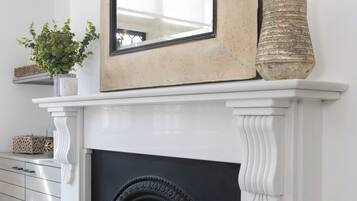 Chimenea blanca con marco negro, un espejo encima y un jarrón decorativo en el repisa.