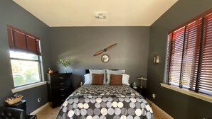 A bedroom with a bed, dresser, nightstand, window, and a wall clock. - UnWIned Arizona (Litchfield Park)