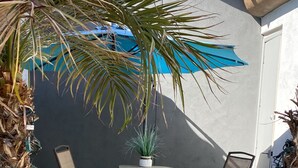 A patio area with a table and two chairs, a potted plant, and a blue umbrella. - UnWIned Arizona (Litchfield Park)