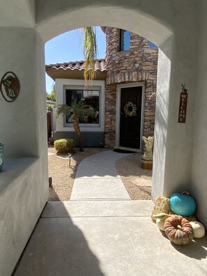 Una casa de piedra con un arco acogedor, una puerta adornada con un adorno floral y un sendero que conduce a la entrada.