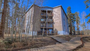 A multi-story building with balconies, surrounded by trees.