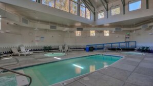 An indoor swimming pool with clear water, surrounded by lounge chairs and a tiled floor.