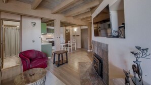 A spacious living area with a fireplace, a red sofa, and a dining table.