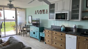 A compact kitchen with teal cabinetry, a white dishwasher, and a ceiling fan. - Hale Kai #116 Direct Oceanfront Condo, just steps to the beach, pool and BBQ! (Lahaina)