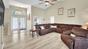 A spacious living room with a large sectional sofa, a wooden coffee table, and a ceiling fan.