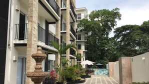 Un immeuble à plusieurs étages doté de balcons, une cour intérieure avec une fontaine et des plantes en pot.