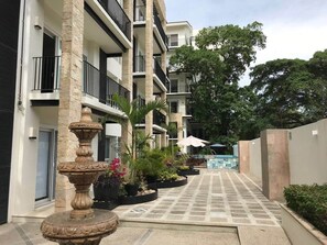A multi-story building with balconies, a central courtyard with a fountain, and potted plants.