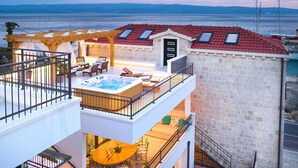 A multi-level outdoor terrace with a hot tub, seating areas, and a view of the sea. - Luxury Villa Indigo with Pool (Split)