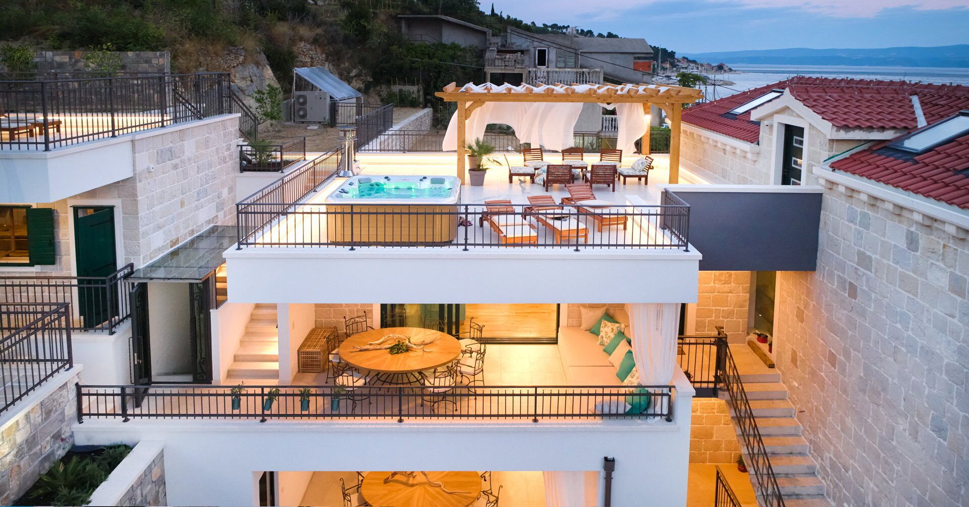 A modern villa with a rooftop terrace, a hot tub, and a dining area.