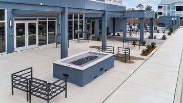 An outdoor area with a fire feature, seating, and a building entrance.