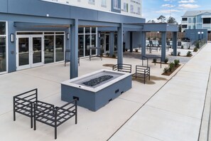An outdoor area with a fire feature, seating, and a building entrance.