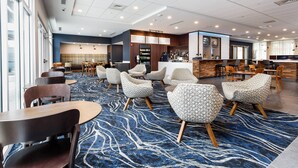 A spacious lobby with modern seating, a bar area, and a view of the outside.