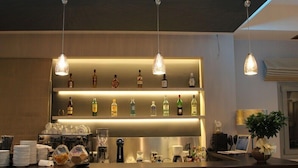 Zona de bar con estantes de botellas de licor, una cafetera y un ordenador portátil sobre la encimera.