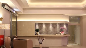 Un moderno vestíbulo de hotel con una recepción, zona de estar y una puerta de cristal que da a una sala privada.