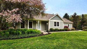 A single-story house with a front porch, a covered entryway, and a well-maintained lawn. - Secluded Cottage Getaway (Saugatuck)